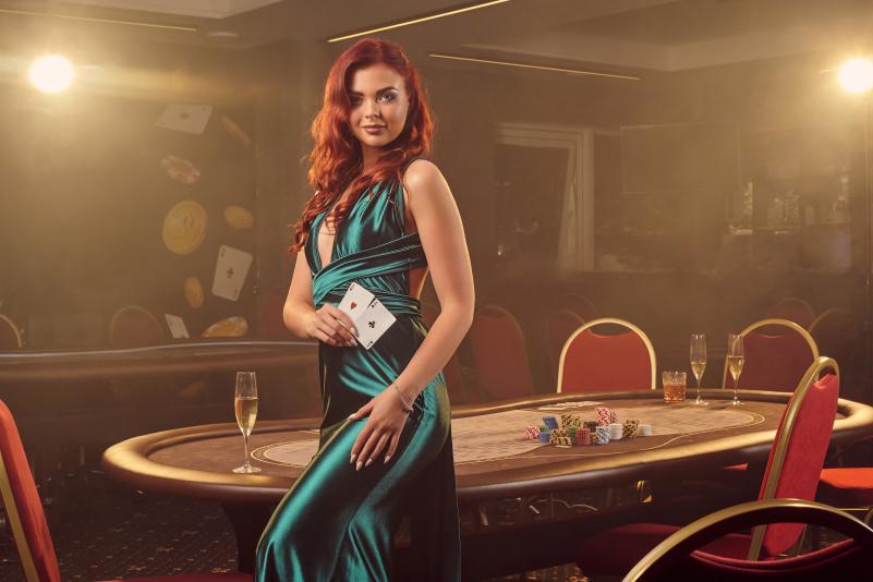 alluring-redheaded-girl-long-blue-satin-dress-is-smiling-posing-sideways-with-two-aces-her-hand-against-poker-table-luxury-casino-passion-cards-chips-alcohol-win-gambling-it-i