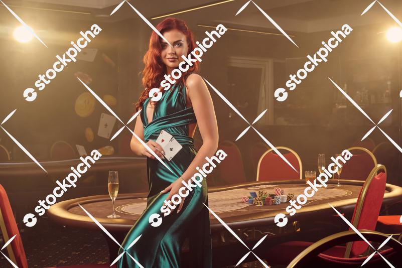 Young beautiful woman is posing against a poker table in luxury casino.