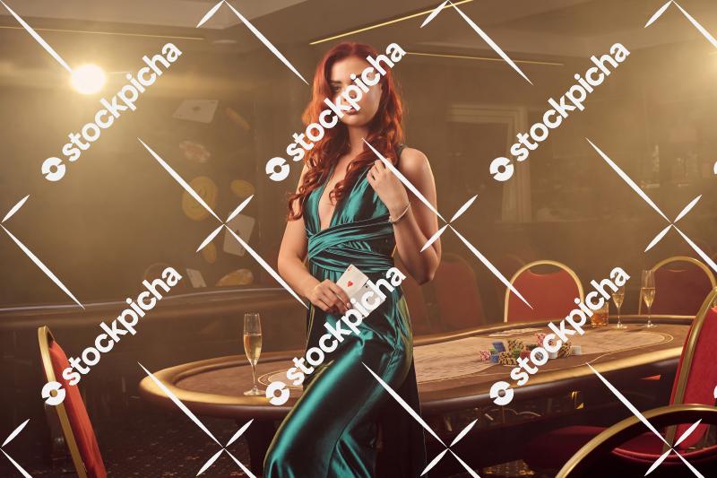 Young beautiful woman is posing against a poker table in luxury casino.