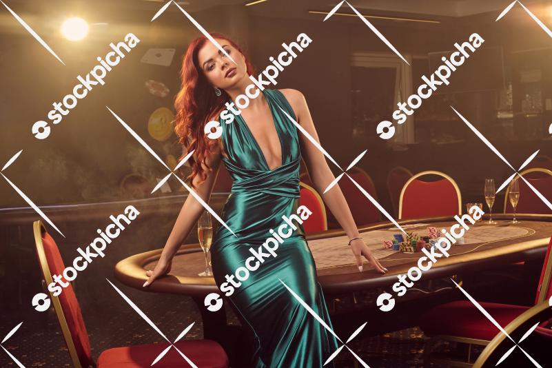 Young beautiful woman is posing against a poker table in luxury casino.