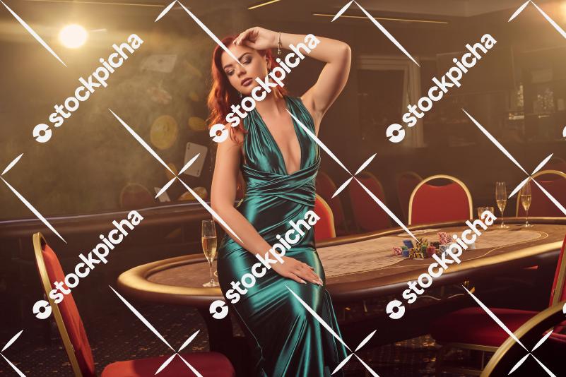 Young beautiful woman is posing against a poker table in luxury casino.